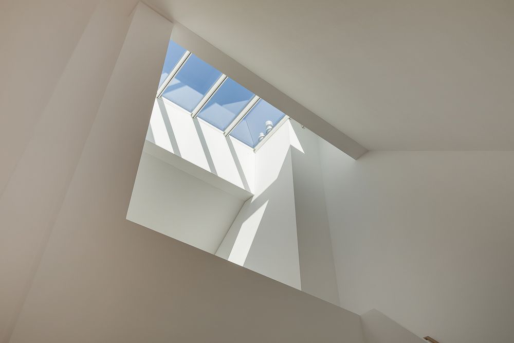 Großes Oberlicht mit mehreren Fenstern in einer weißen Decke, Sonnenlicht fällt herein.