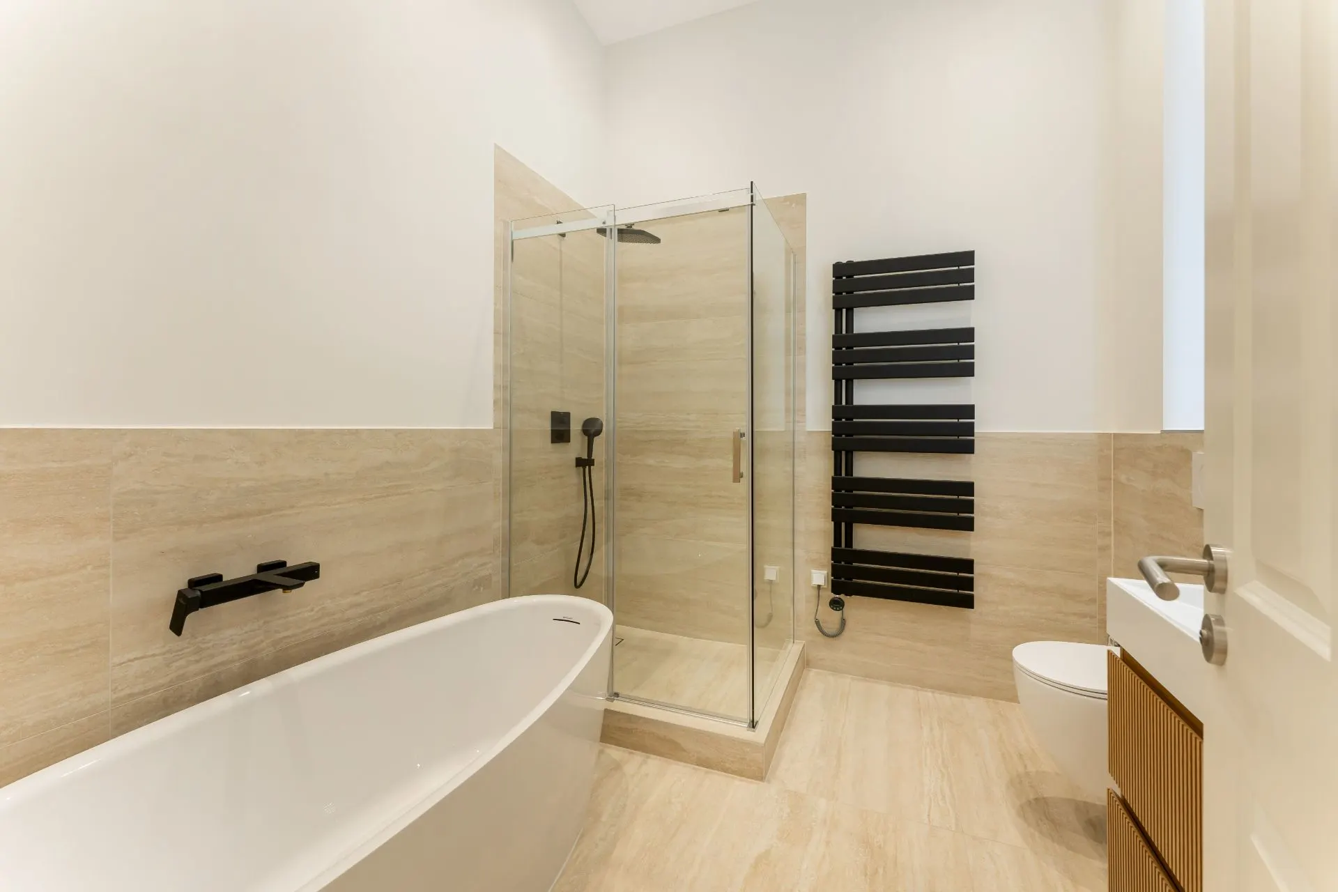 Modernes Badezimmer mit Badewanne, Glasdusche, WC und Handtuchheizung.