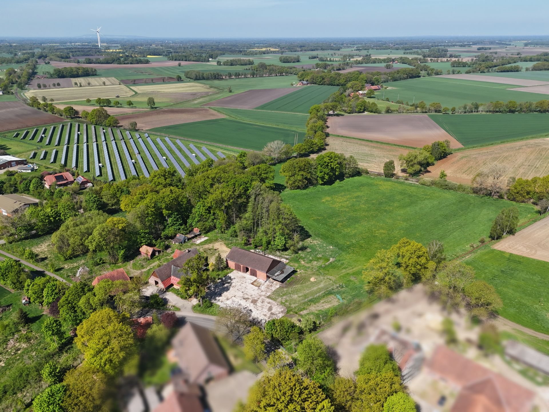 Luftaufnahme eines Wohnhauses mit Garten und umliegenden Feldern auf dem Land.