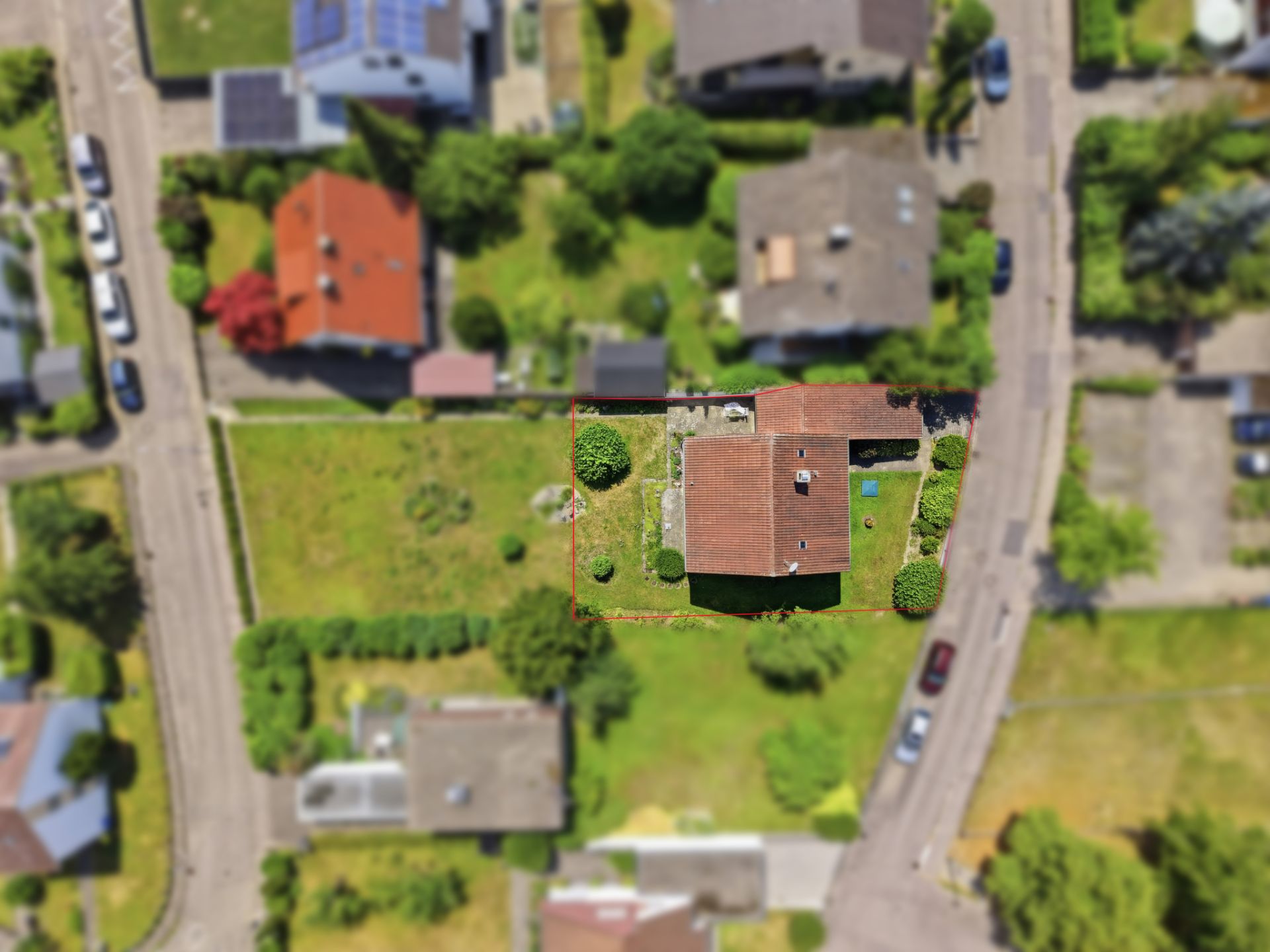 Luftaufnahme eines Wohnhauses mit Garten in einem Wohngebiet, umgeben von Straßen und weiteren Häusern.