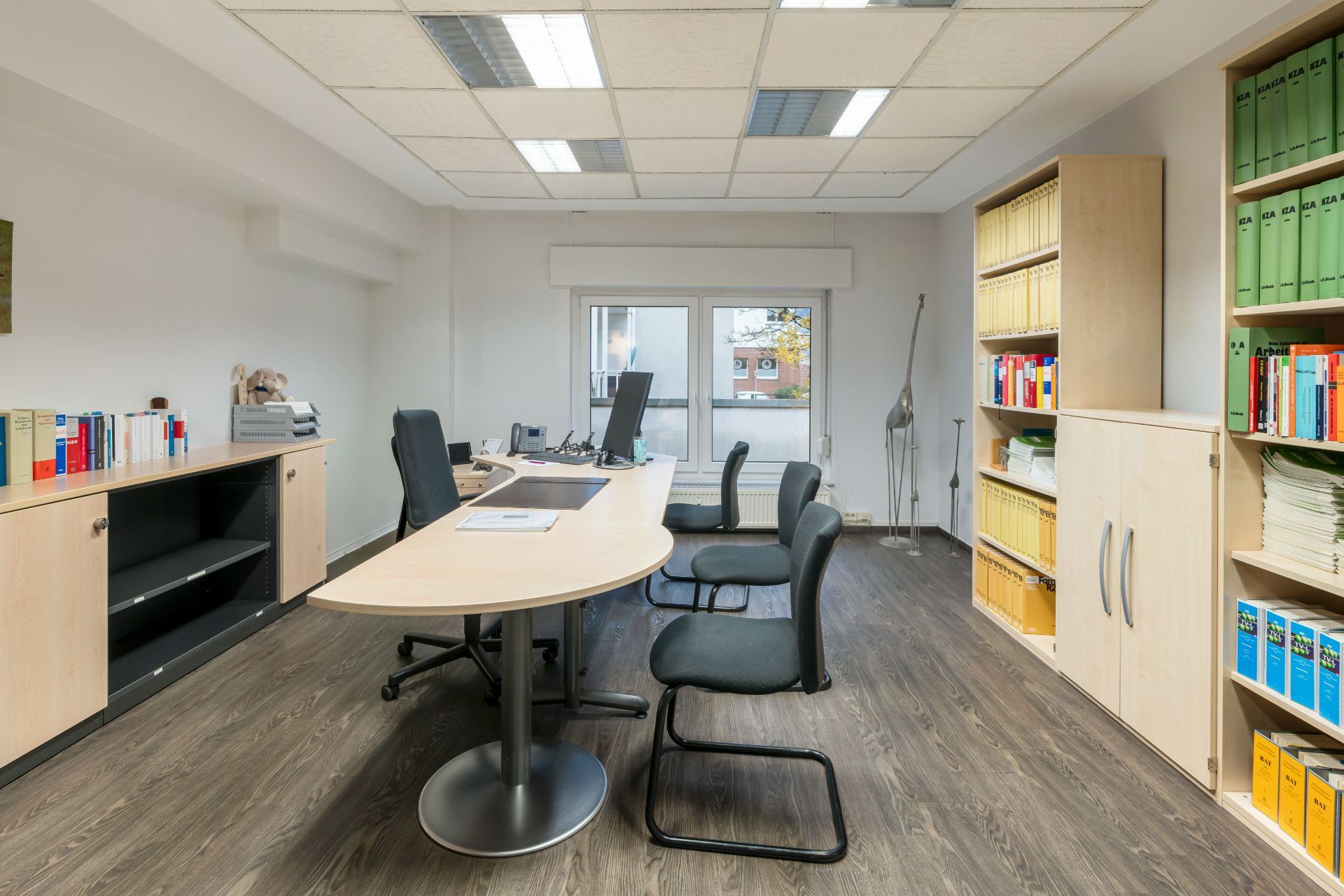 Modernes Büro mit Schreibtisch, Stühlen, Regalen und Fenstern, Holzfußboden.