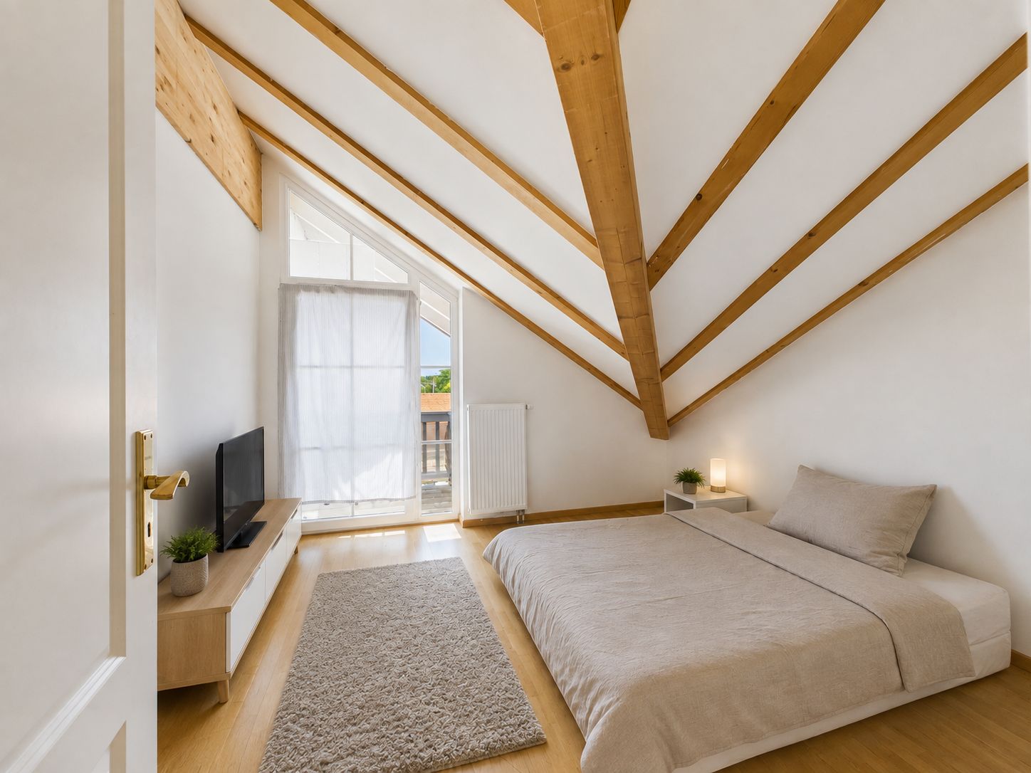 Modernes Schlafzimmer mit schräger Decke, Bett, Teppich, TV und Fenster mit Tageslicht.