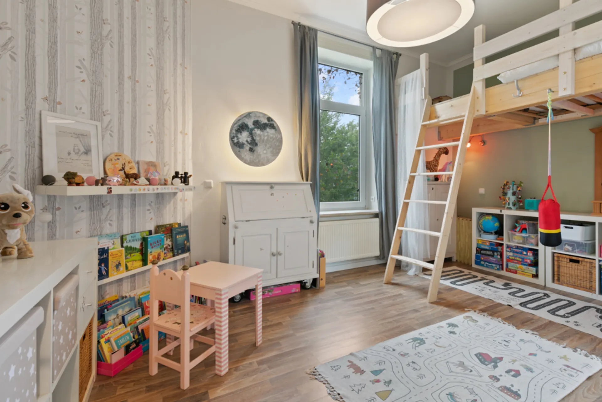 Helles Kinderzimmer mit Hochbett, Bücherregal, Spielzeug, Tisch und Stuhl auf Holzboden.