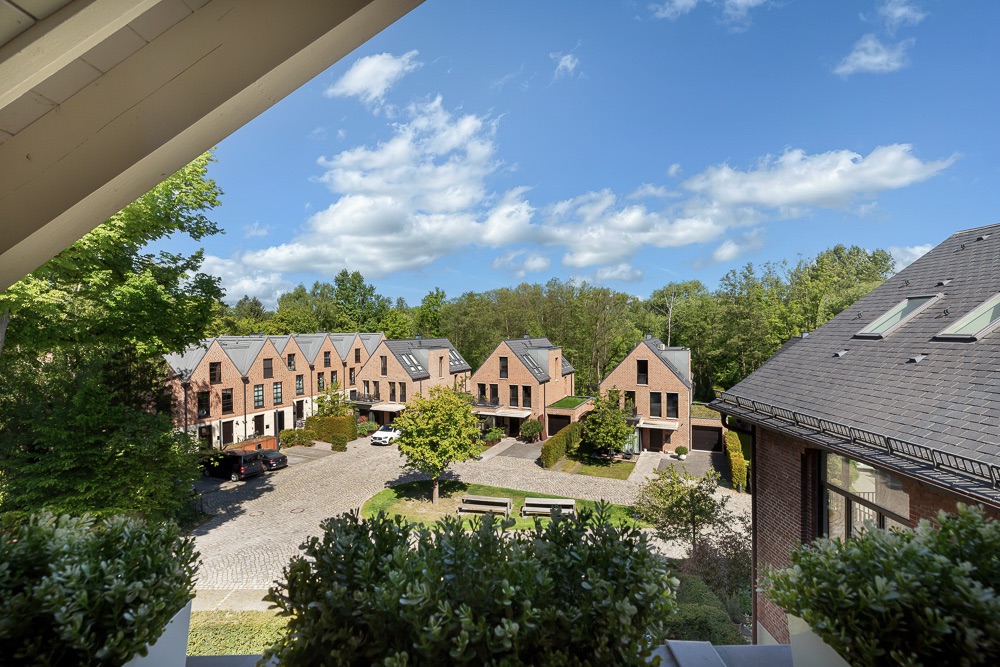 Blick auf einen Innenhof mit mehreren Backsteinhäusern und Bäumen bei blauem Himmel.