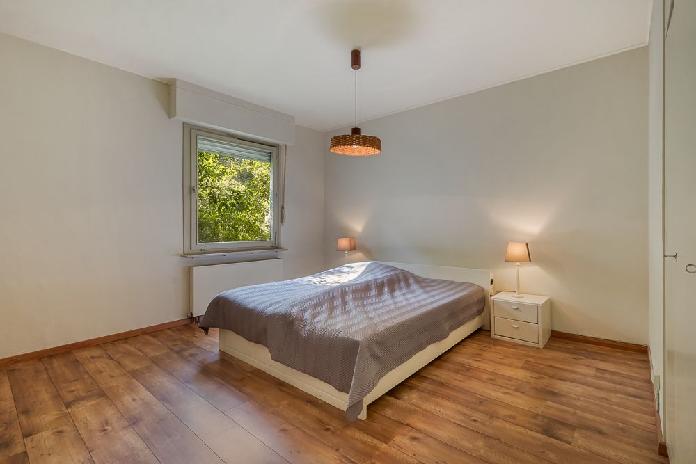 Schlafzimmer mit Doppelbett, zwei Nachttischen, zwei Lampen und Fenster mit Blick ins Grüne.