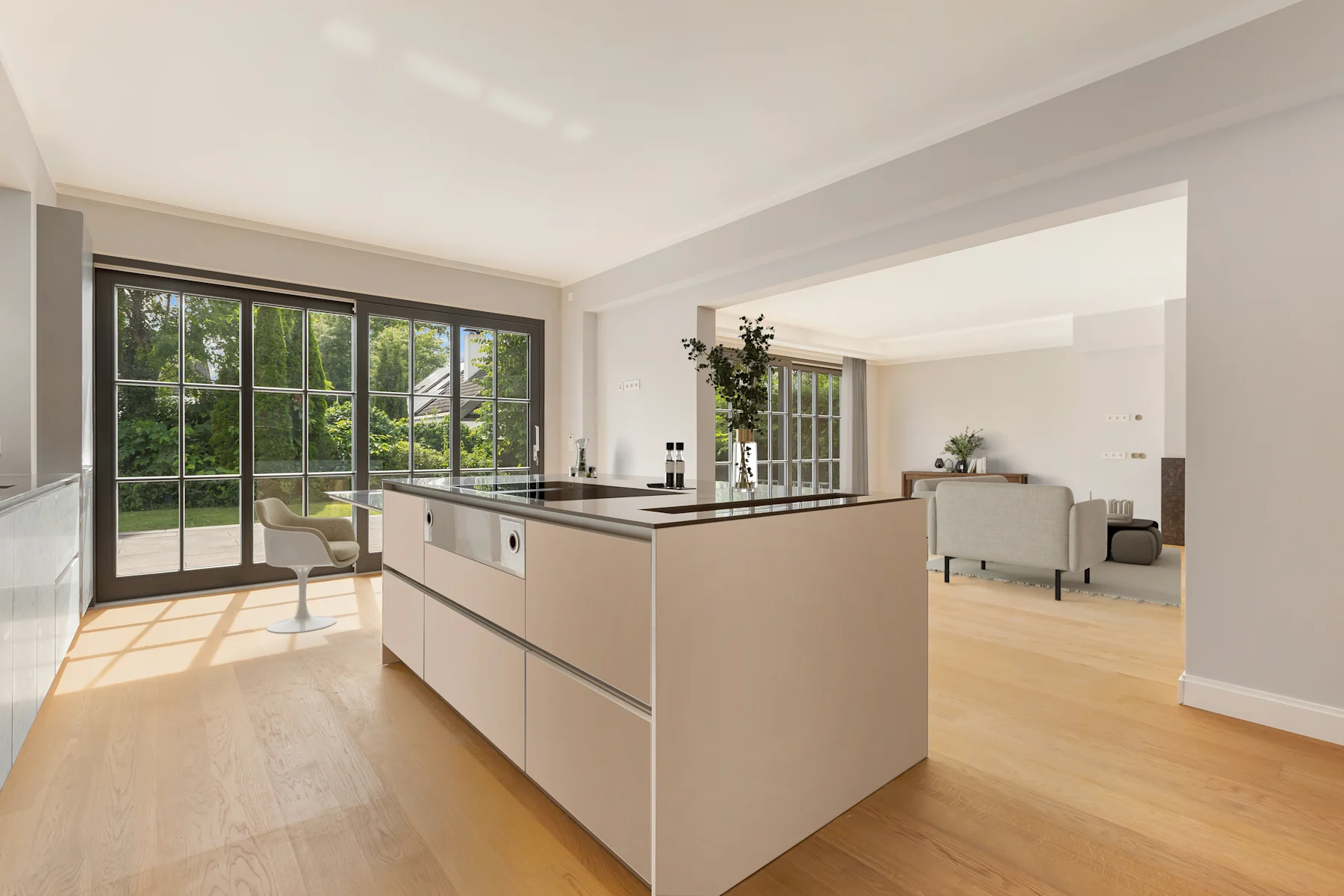 Moderne Küche mit Kochinsel und großem Fenster, dahinter ein Wohnzimmer mit Sofa.