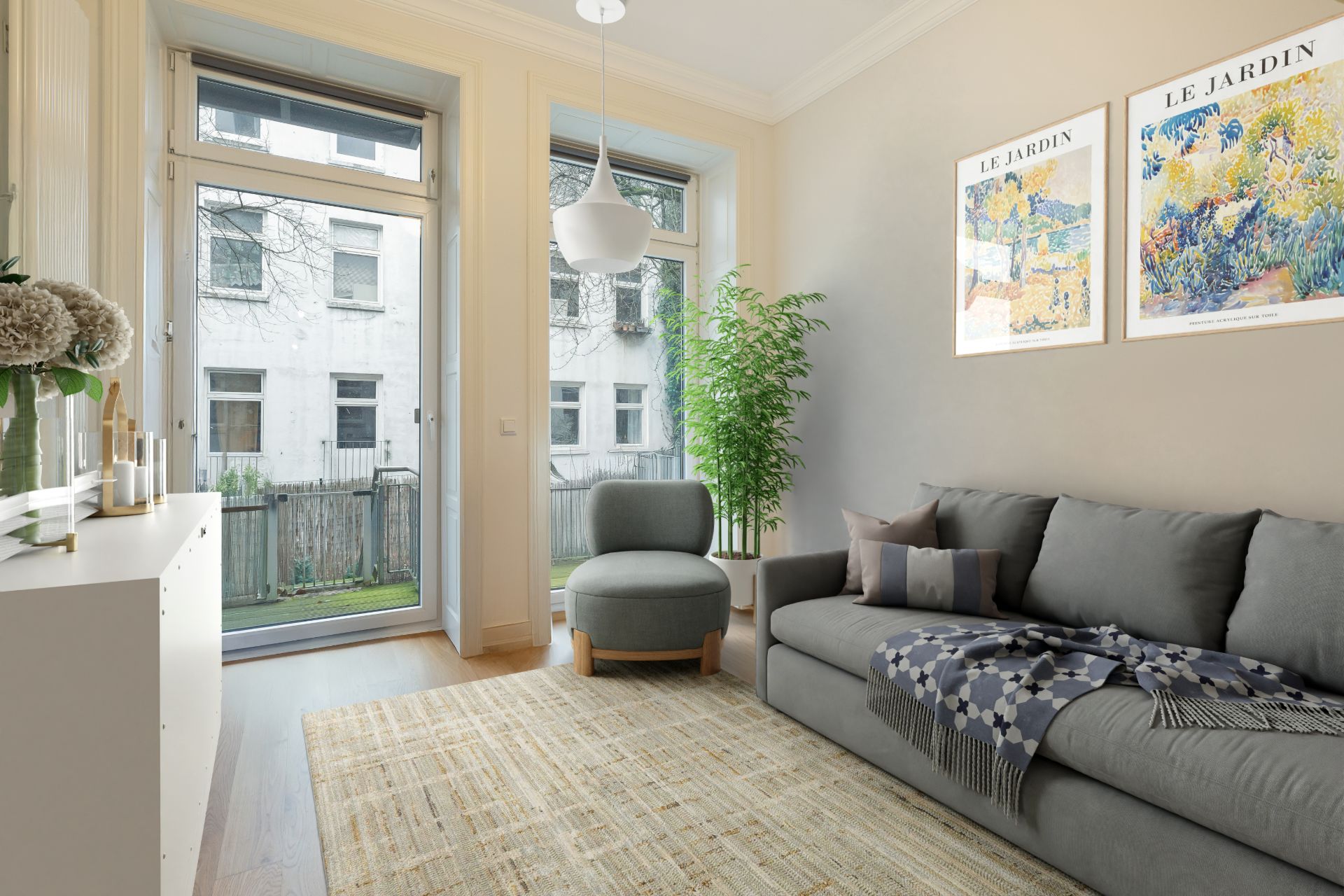 Helles Wohnzimmer mit grauem Sofa, Sessel, großem Fenster und zwei Bildern an der Wand.