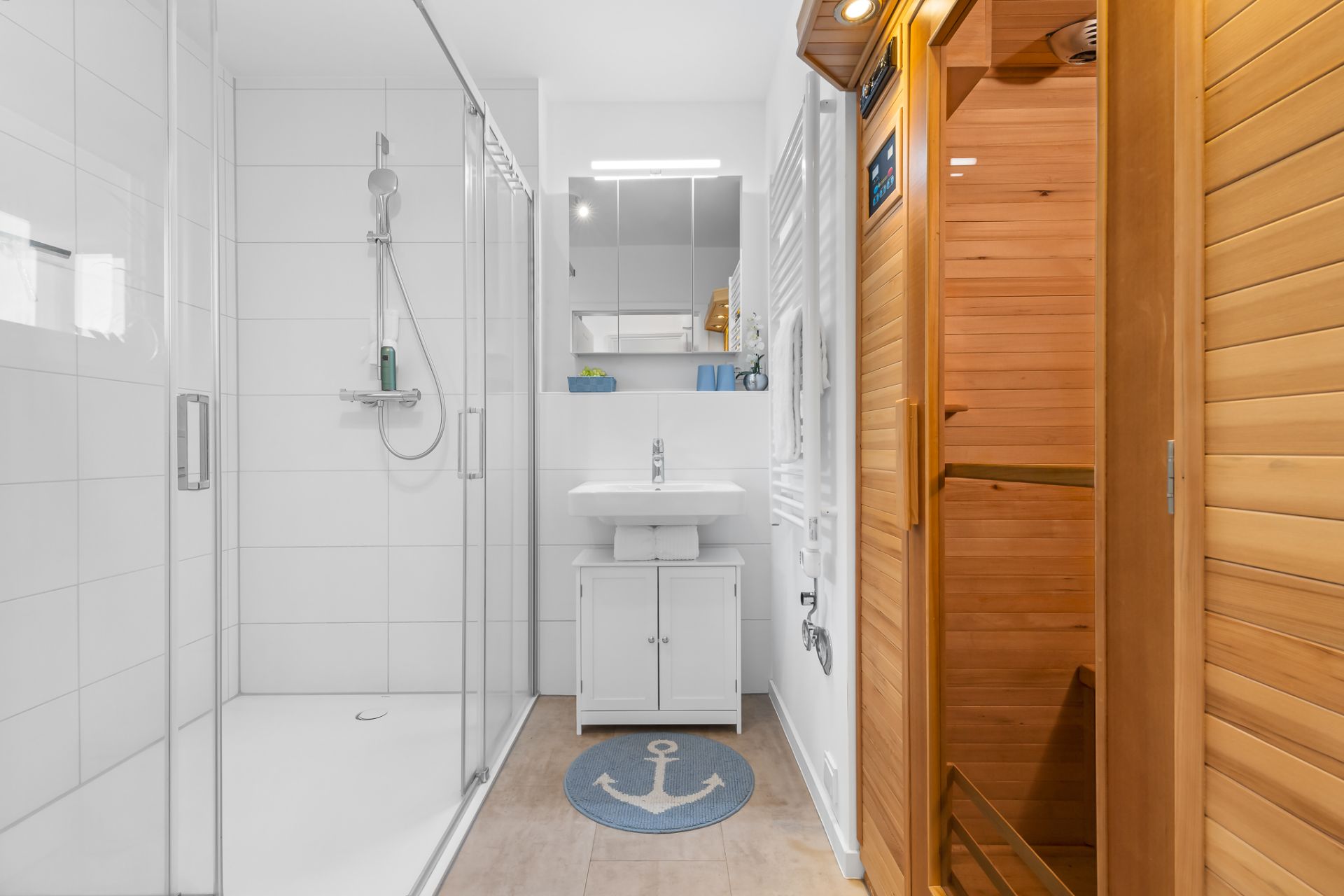 Modernes Bad mit Dusche, Waschbecken, Spiegel und Holzsauna, Ankerteppich auf dem Boden.