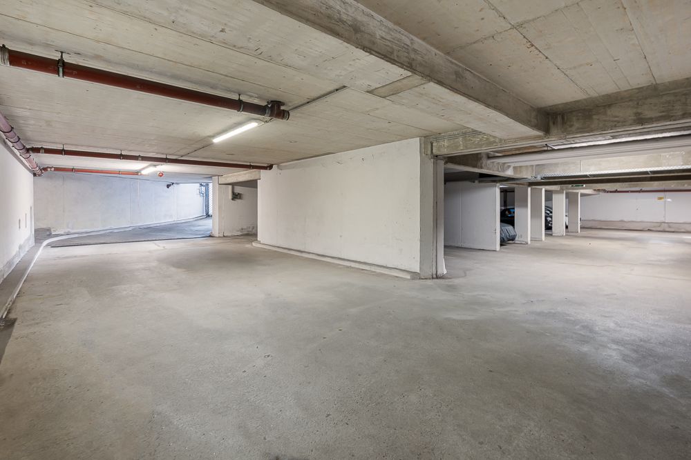 Leere Tiefgarage mit Betonboden und Wänden, wenigen sichtbaren Stellplätzen.