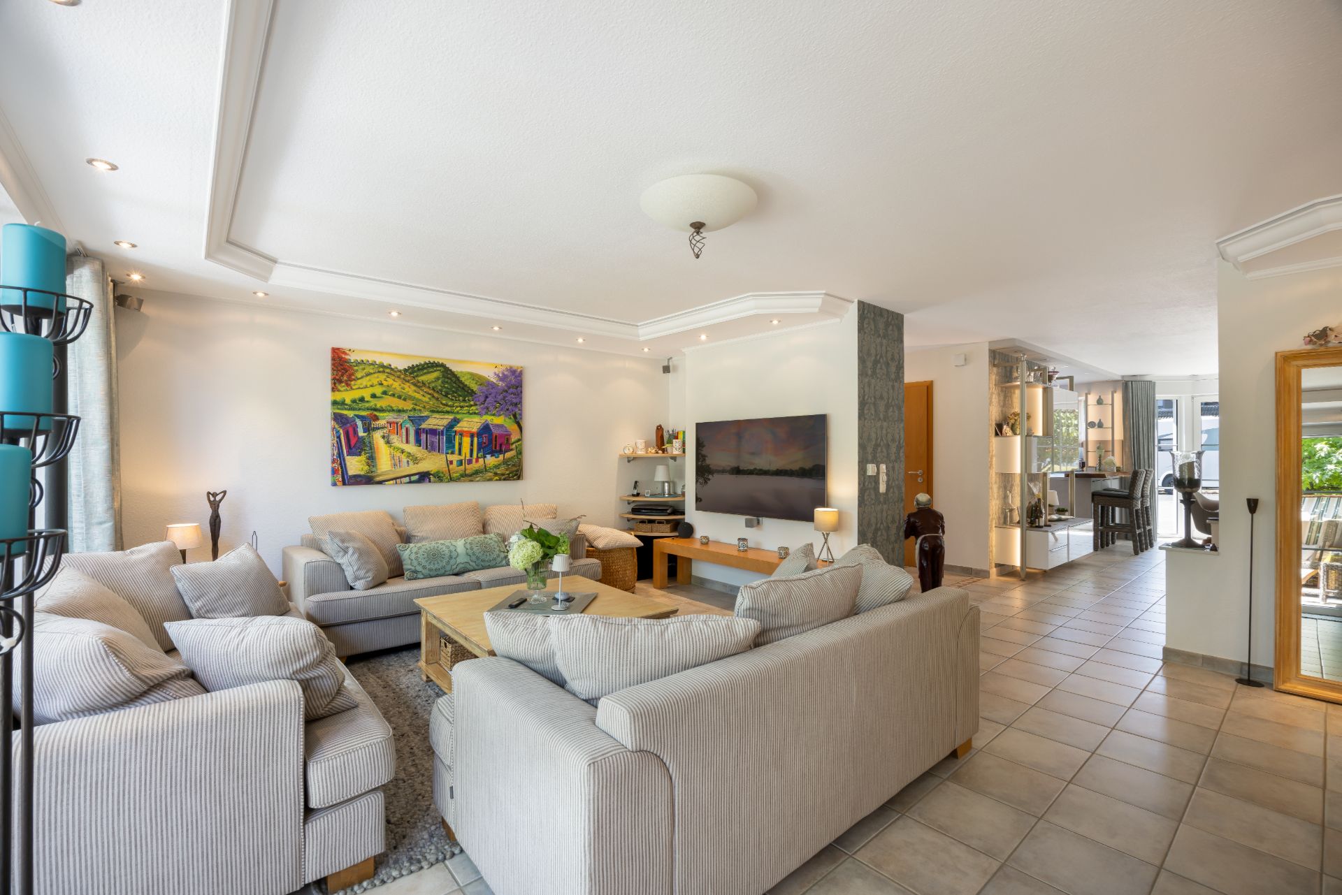 Modernes Wohnzimmer mit zwei Sofas, Couchtisch, Fernseher und farbigem Gemälde an der Wand.
