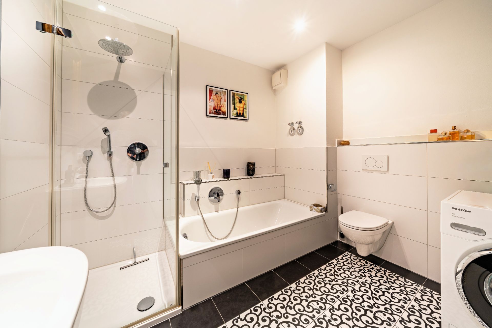 Modernes Badezimmer mit Dusche, Badewanne, WC, Waschmaschine und zwei Bildern an der Wand.