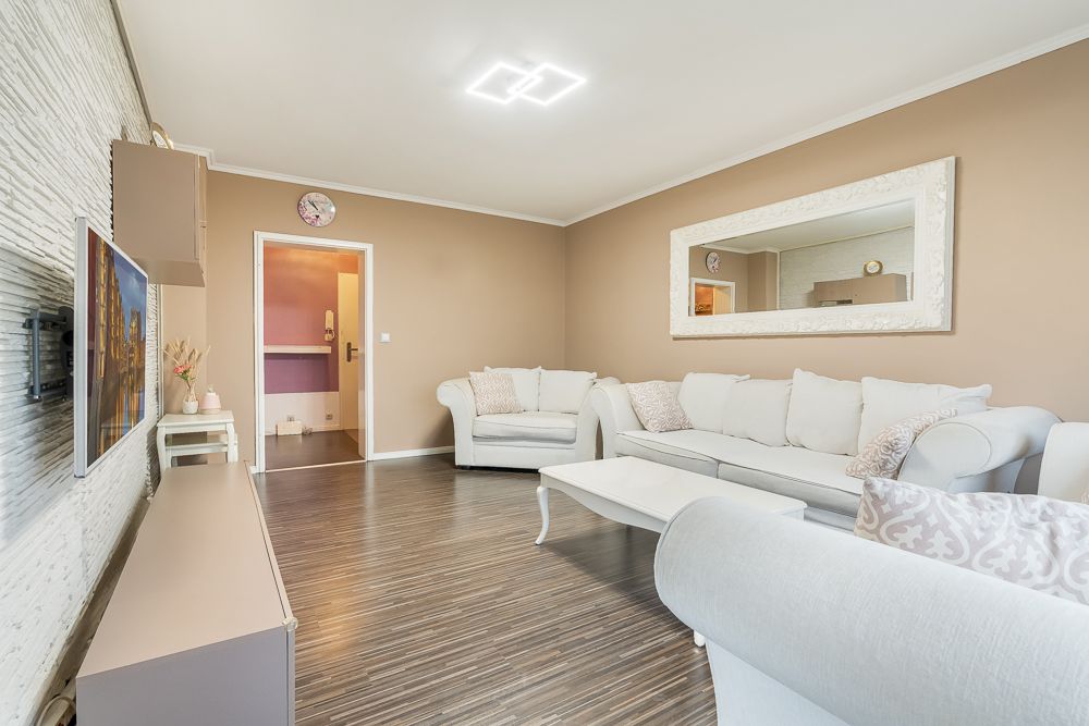 Helles Wohnzimmer mit weißen Sofas, Couchtisch, Wandspiegel und Holzfußboden.