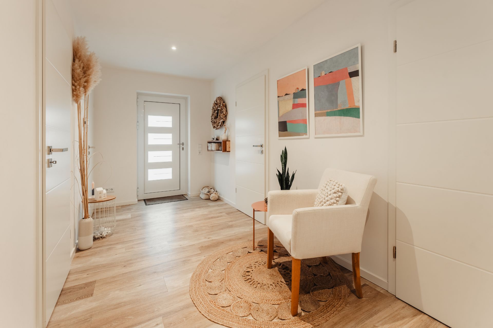 Heller Flur mit Holzboden, weißem Stuhl, Pflanzen und moderner Wanddekoration.