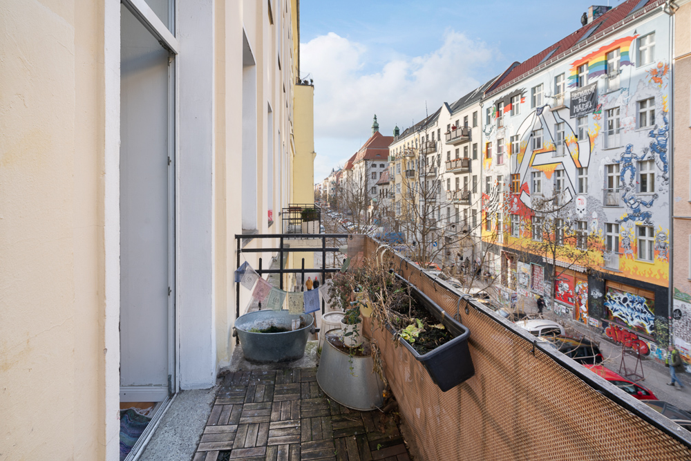Balkon mit Pflanzen und Blick auf eine bunte, mit Graffiti verzierte Hausfassade.