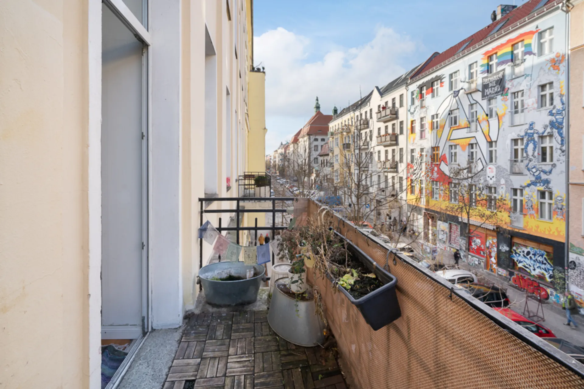 Balkon mit Pflanzen und Blick auf eine bunte, mit Graffiti verzierte Hausfassade.