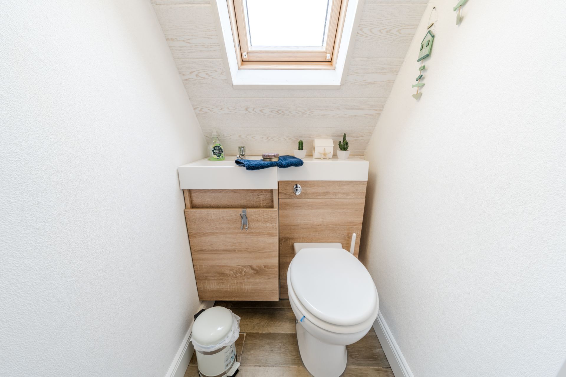 Kleines Badezimmer mit Toilette, Waschbecken und Dachfenster.