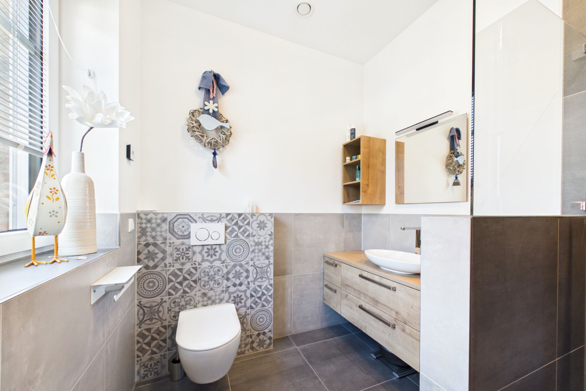 Modernes Badezimmer mit Wandtoilette, Holzwaschtisch und dekorierten Fliesen.