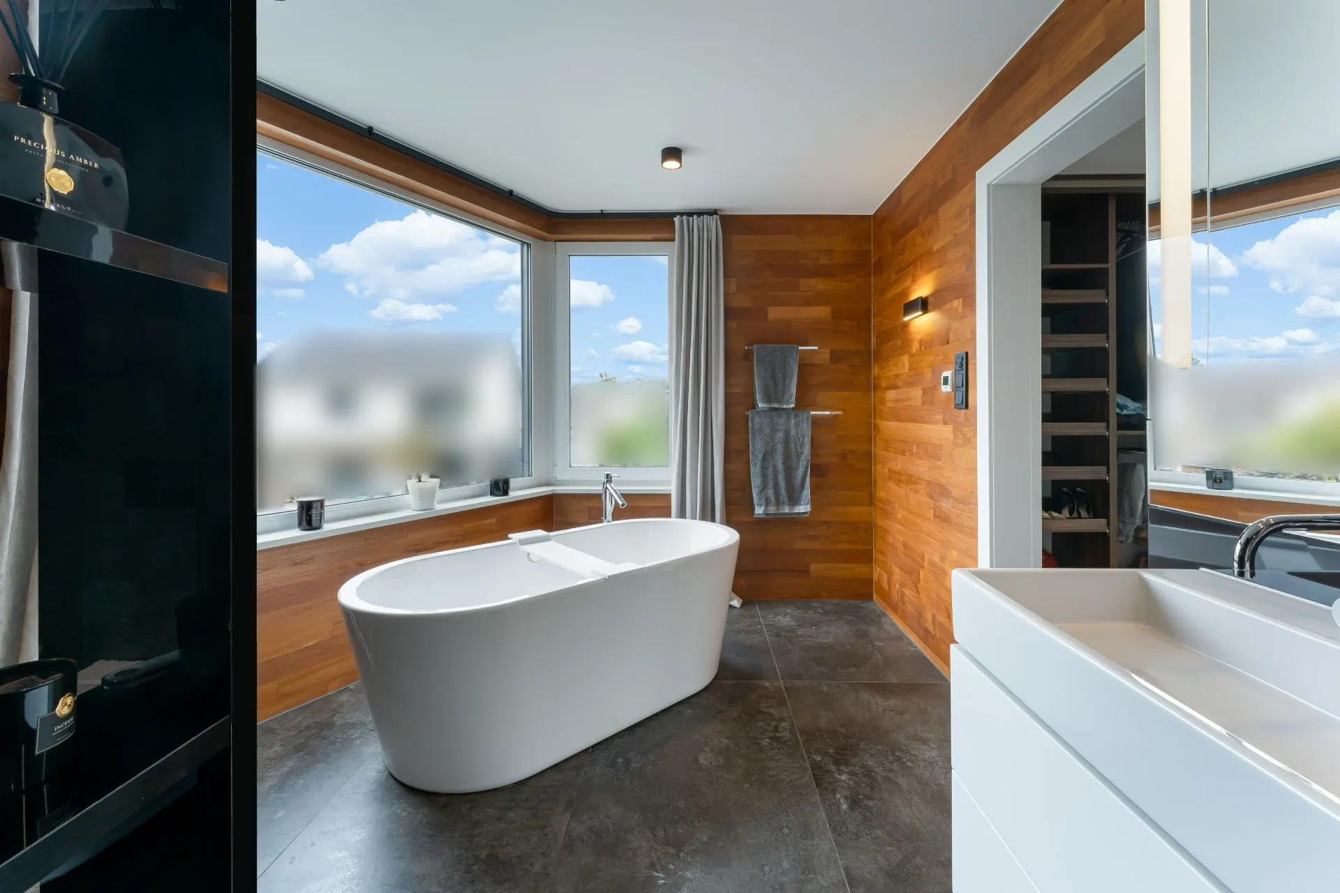 Modernes Bad mit freistehender Badewanne, großem Fenster und Holzverkleidung.