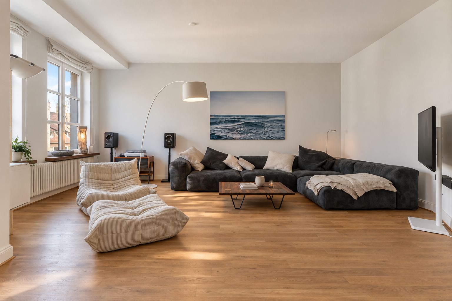 Helles Wohnzimmer mit großem Ecksofa, zwei Sesseln, Couchtisch und großem Fenster.
