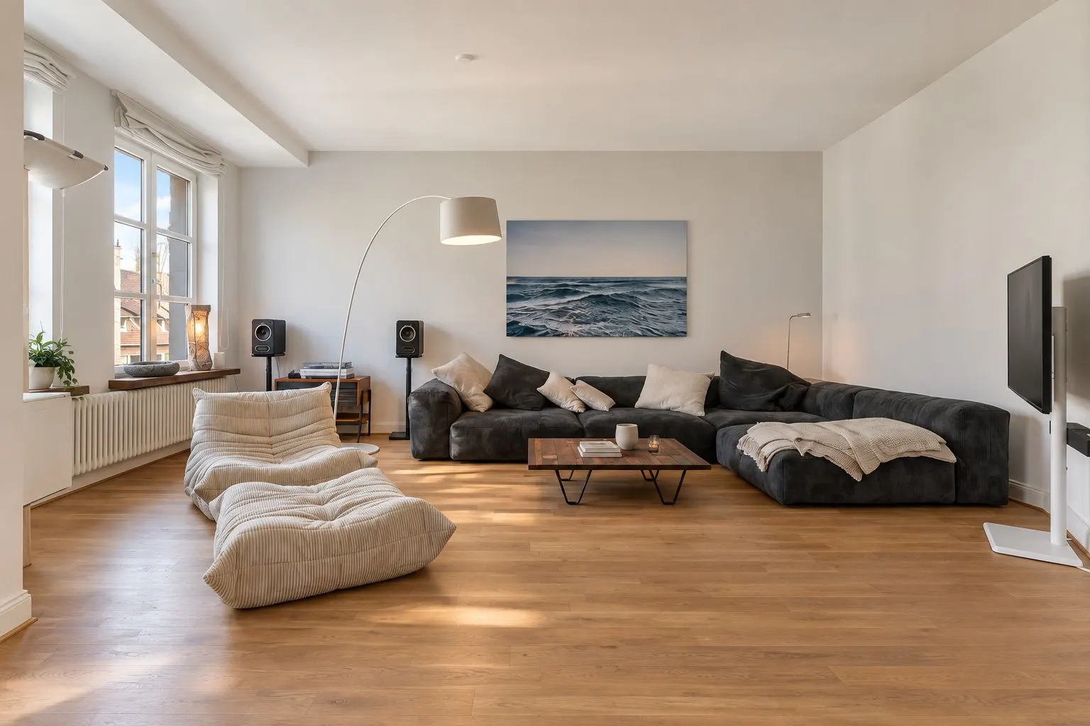 Helles Wohnzimmer mit großem Ecksofa, zwei Sesseln, Couchtisch und großem Fenster.