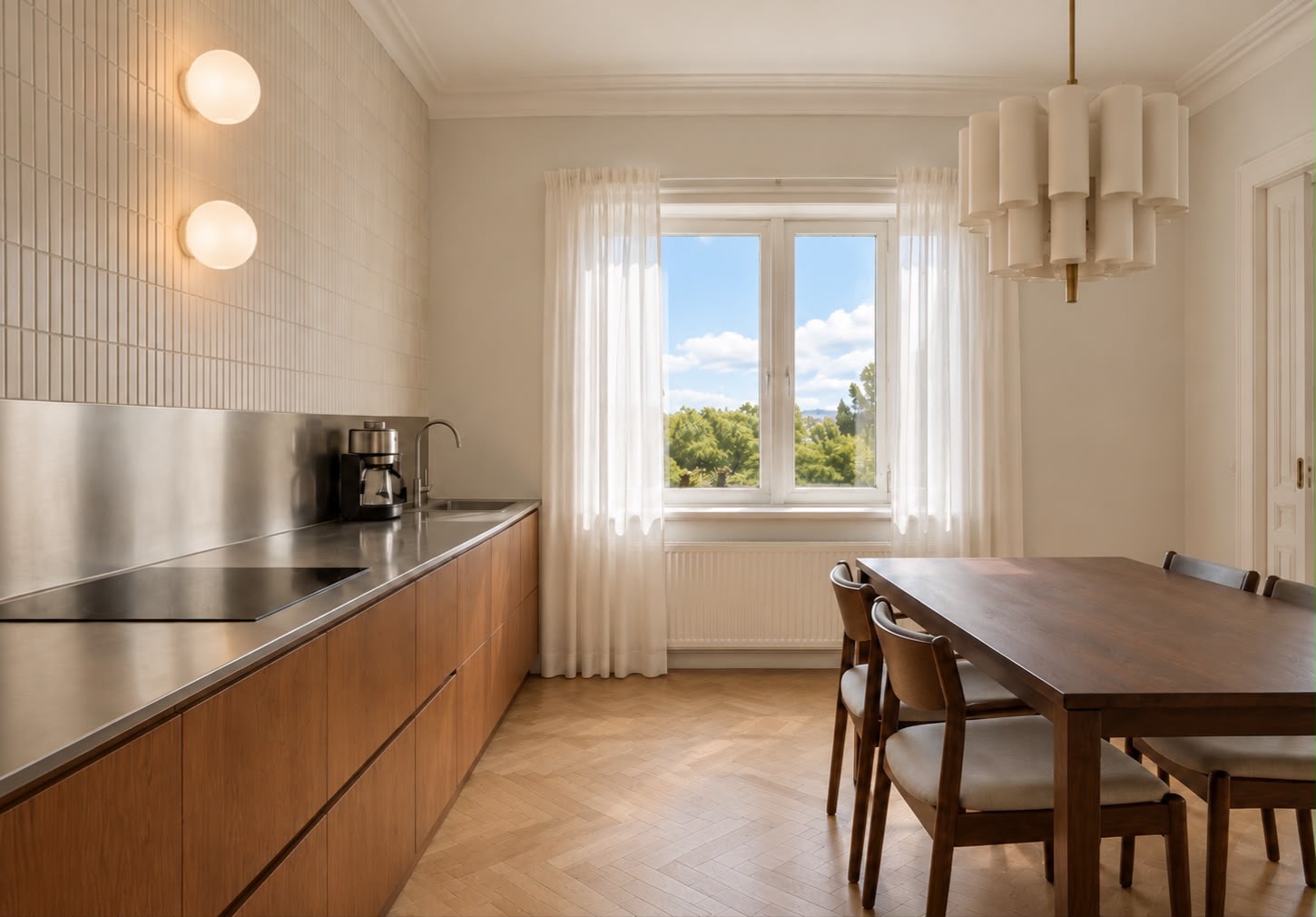 Helle Küche mit Holzboden, Esstisch, vier Stühlen und großem Fenster mit Blick ins Grüne.