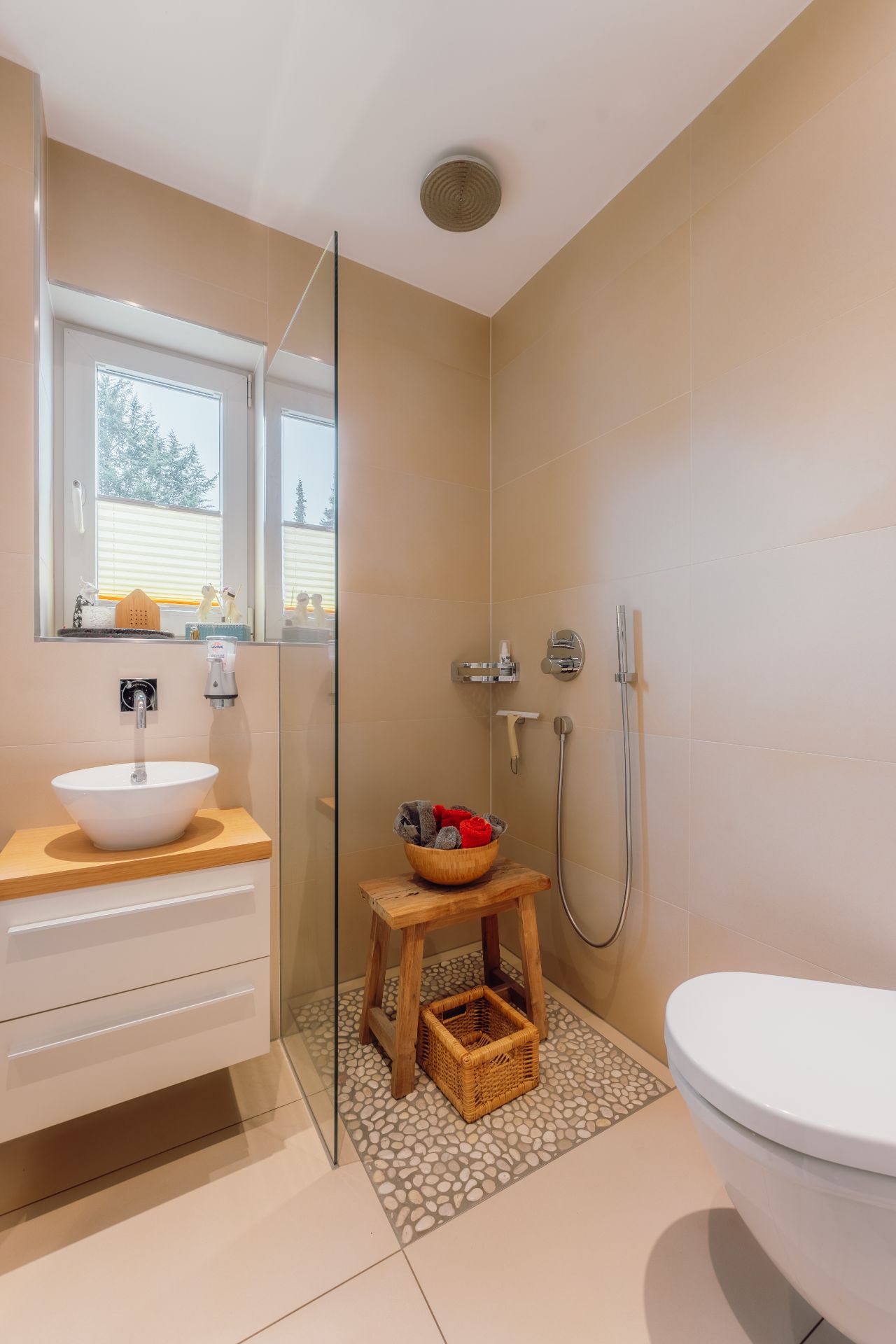 Modernes Badezimmer mit Dusche, Waschbecken und Hocker auf hellem Fliesenboden.