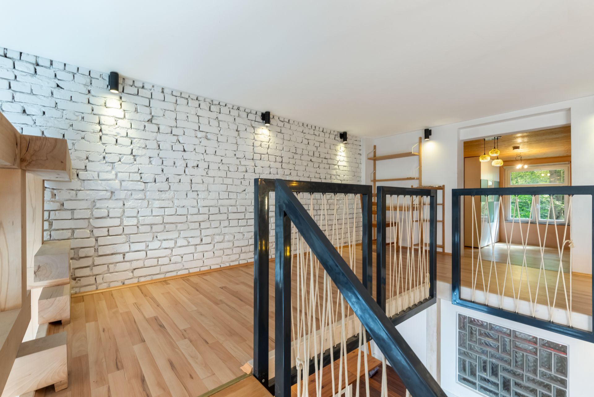 Innenraum mit weißer Backsteinwand, Holztreppe und hellen Holzböden.