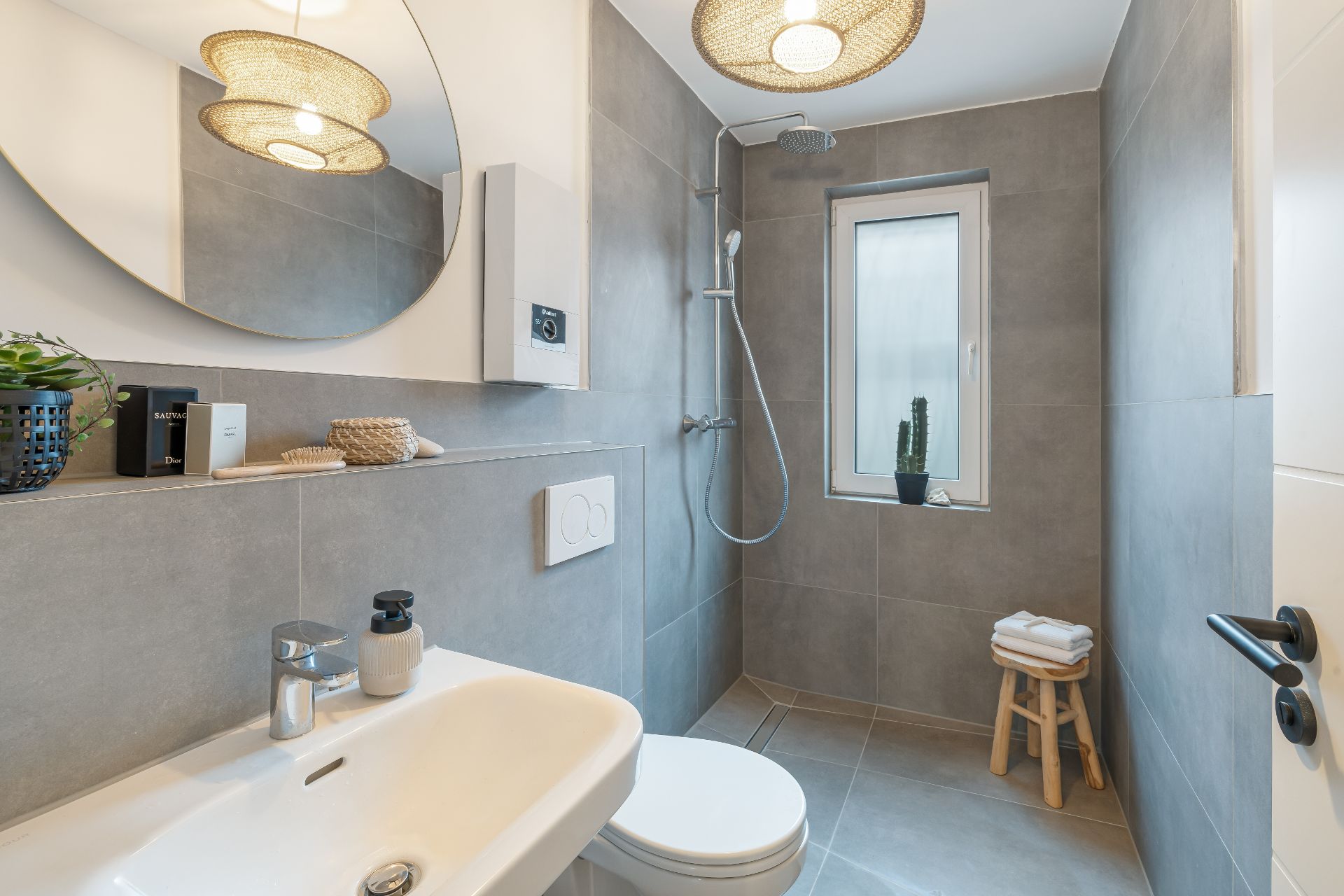 Modernes Badezimmer mit Spiegel, Waschbecken, Toilette, Dusche und Fenster.