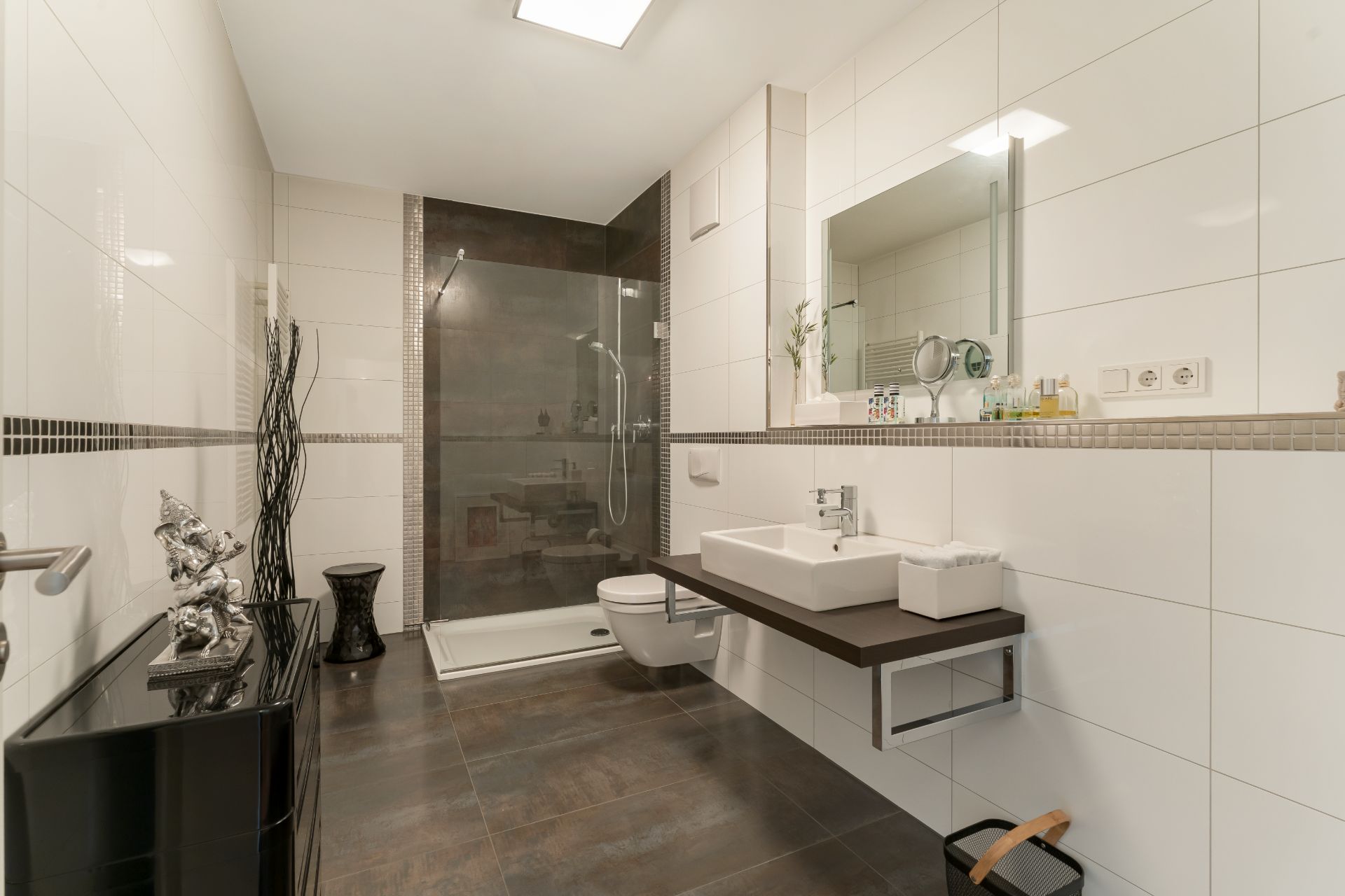 Modernes Badezimmer mit großer Dusche, Waschtisch, Spiegel und weiß gefliesten Wänden.