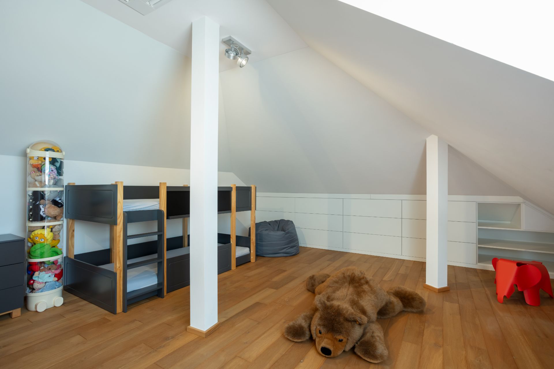 Kinderzimmer im Dachgeschoss mit Holzfußboden, Etagenbett, Stofftieren und Spielzeug.