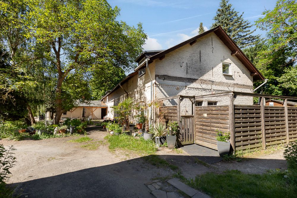 Außenansicht eines Wohnhauses mit Garten, vielen Pflanzen und Holzzaun bei sonnigem Wetter.