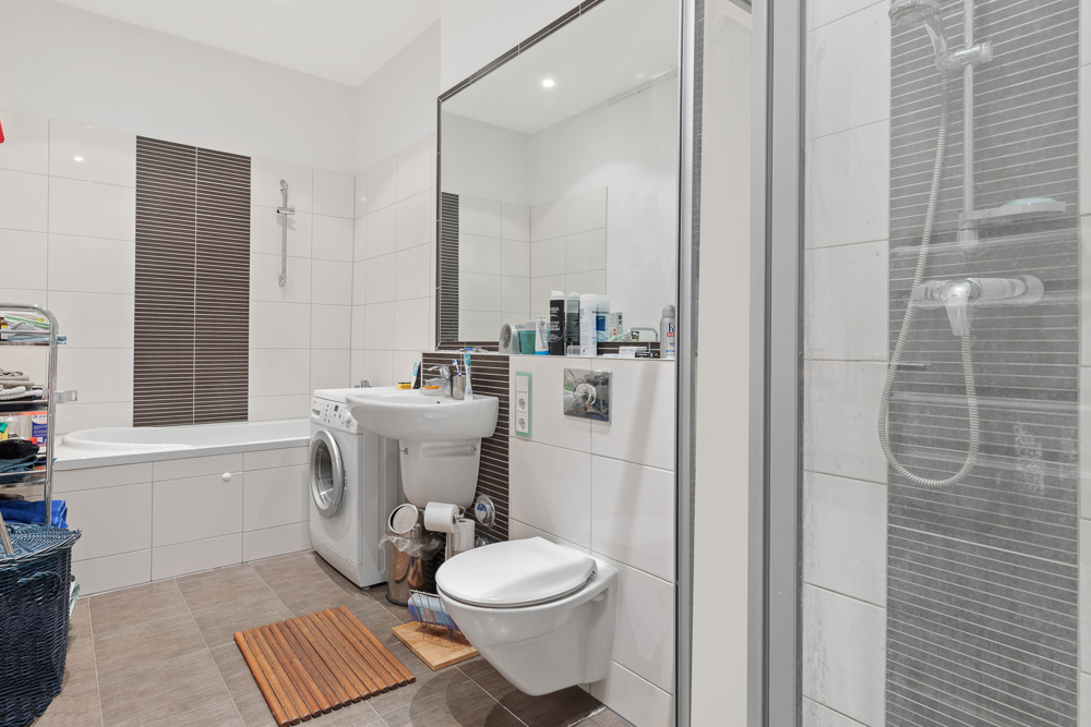 Modernes Badezimmer mit Badewanne, Dusche, Waschbecken, Waschmaschine und Toilette.