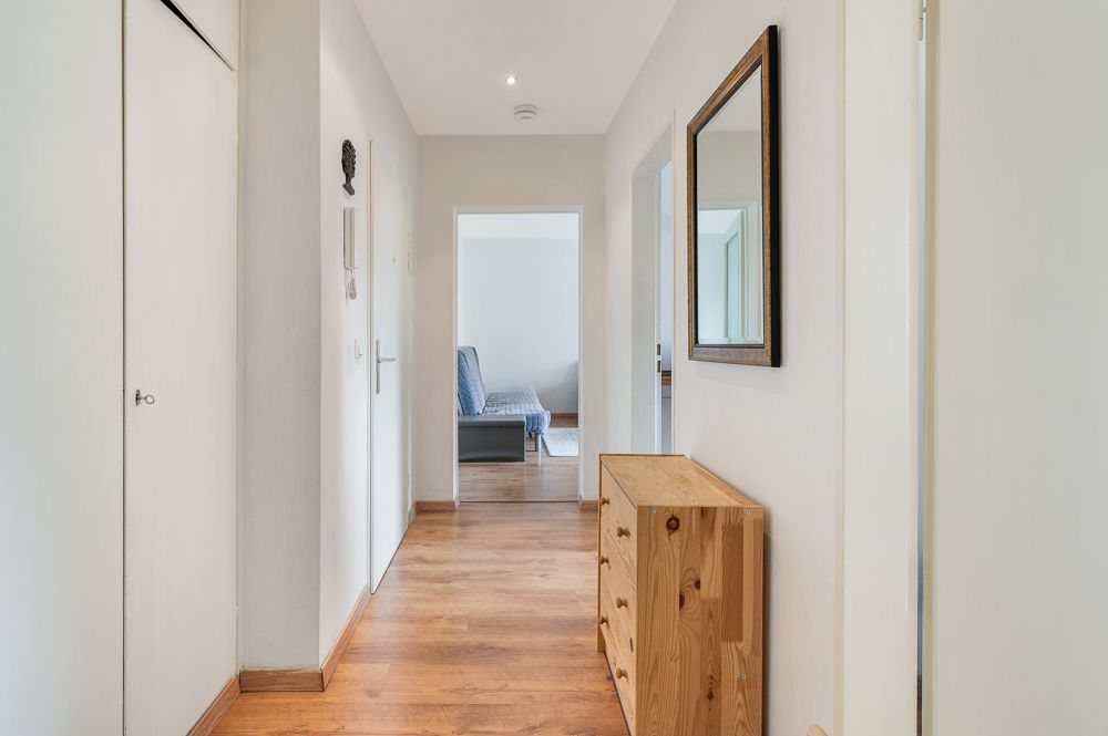 Heller Flur mit Holzkommode und Spiegel, Türen führen in weitere Räume.