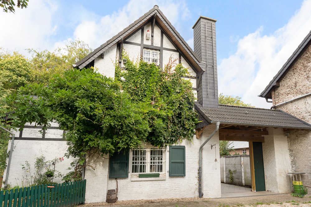 Weißes Fachwerkhaus mit grün bewachsener Fassade und grünen Fensterläden.