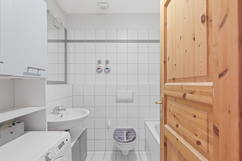 Kleines Badezimmer mit Waschbecken, Toilette, Badewanne und Waschmaschine.