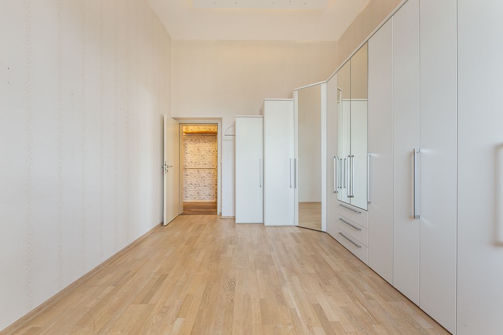 Heller Raum mit Holzfußboden und weißen Einbauschränken an der Wand.