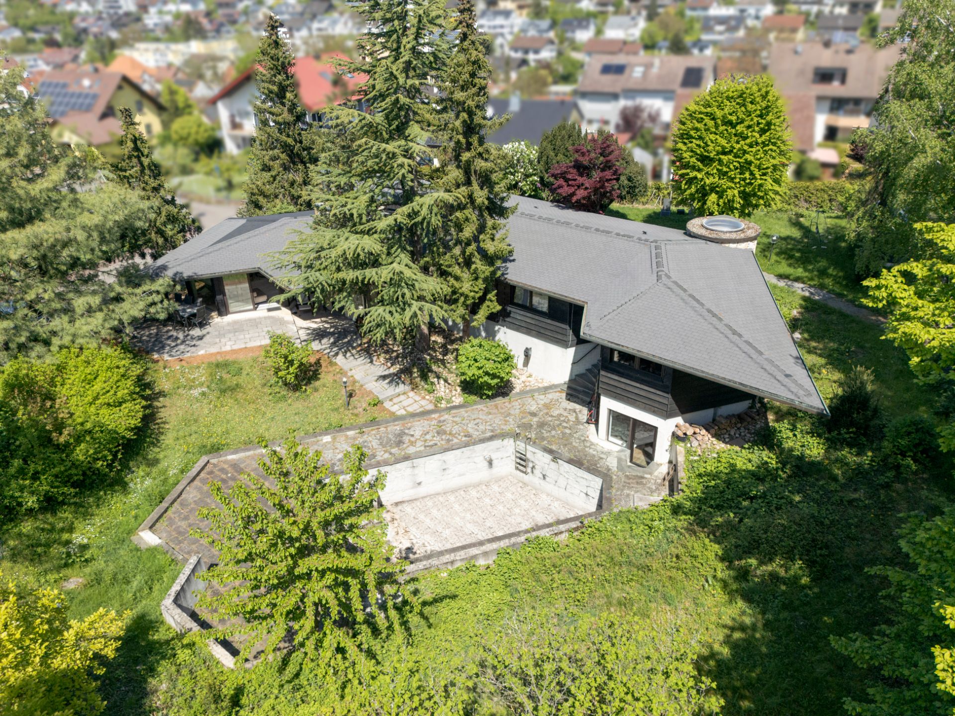 Luftaufnahme eines Einfamilienhauses mit Garten, Bäumen und einer Terrasse.