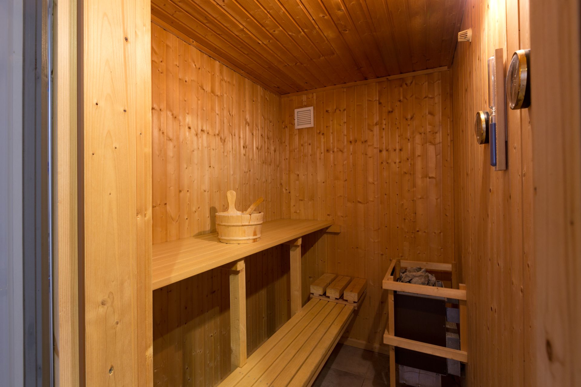 Holzsauna mit zwei Bänken, Eimer und Saunaofen.