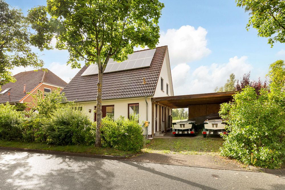 Einfamilienhaus mit Solaranlage auf dem Dach und überdachtem Carport neben dem Haus.