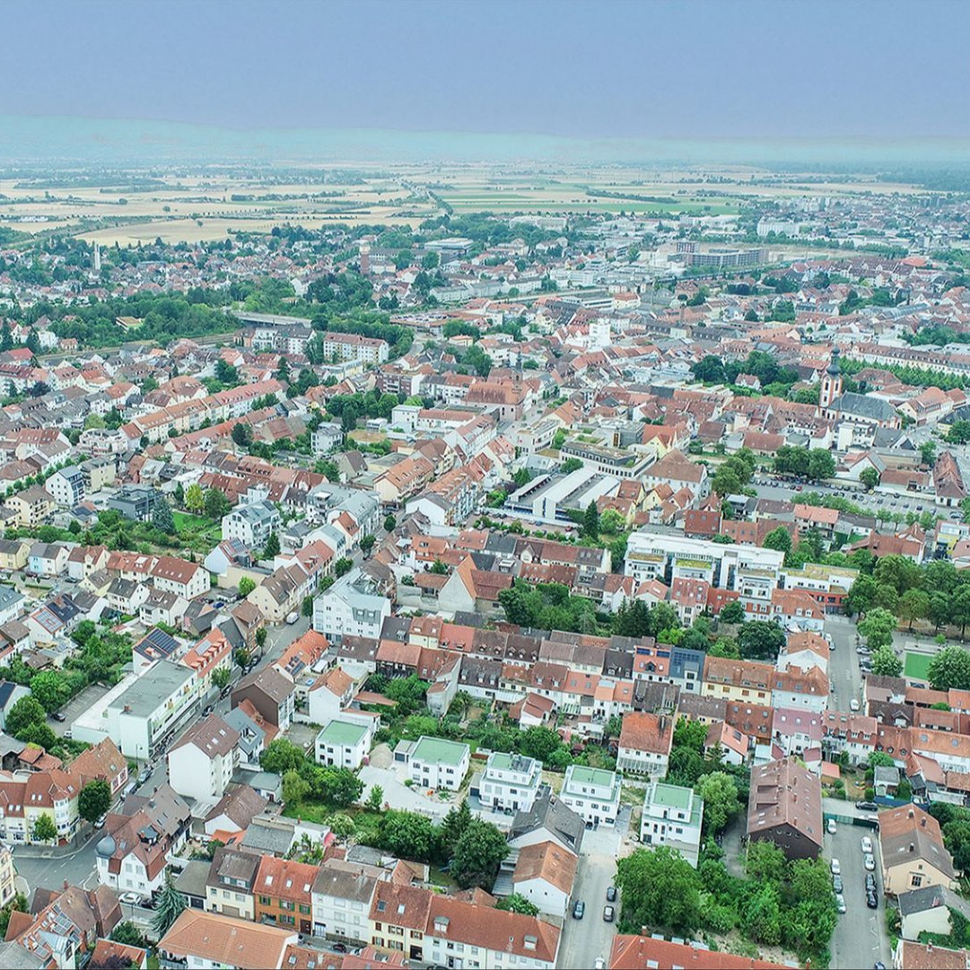 Luftaufnahme einer Wohngegend mit vielen Häusern, Straßen und etwas Grünfläche.