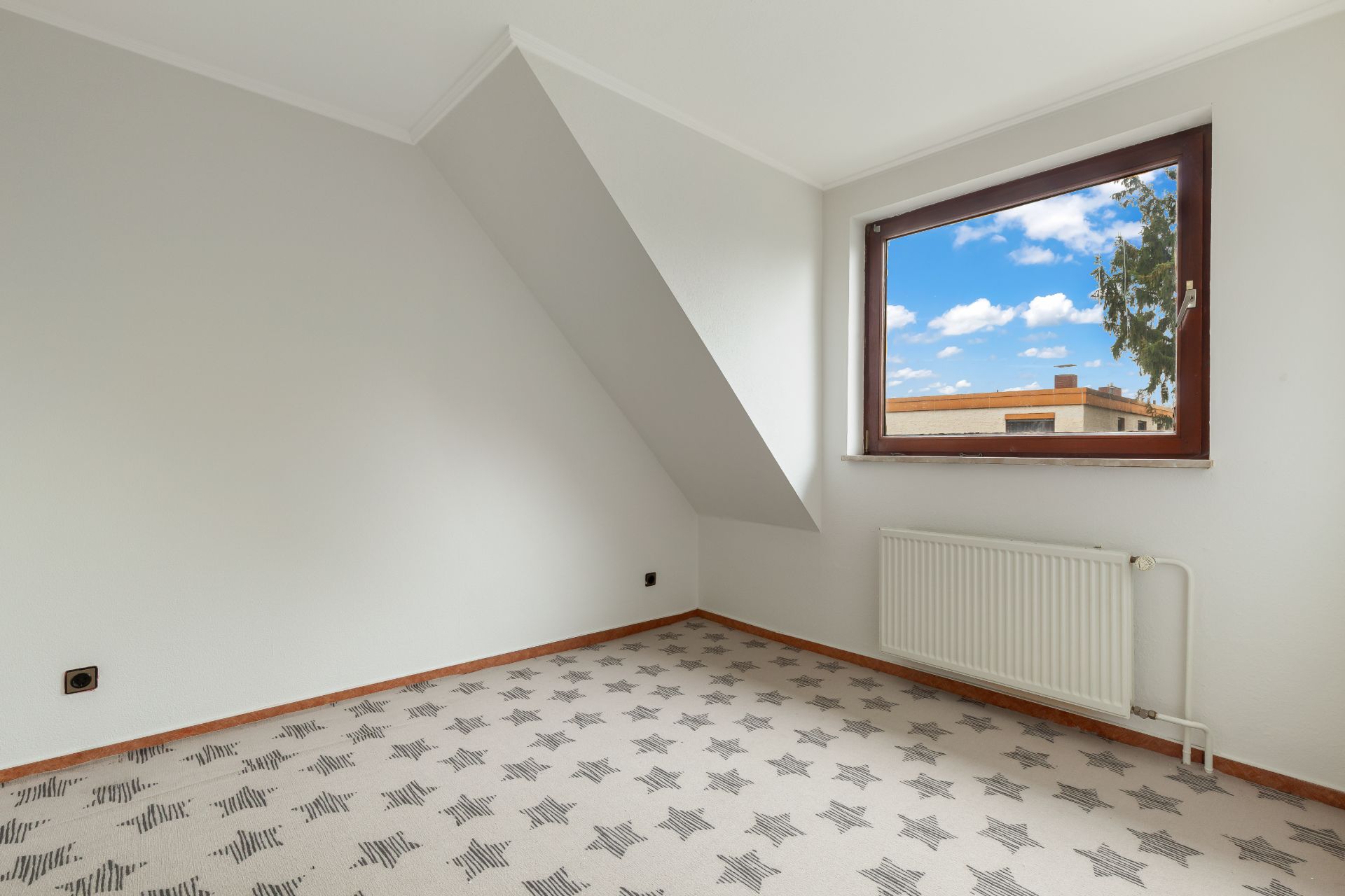 Helles Zimmer mit Sternenmusterteppich, weißer Wand, großem Fenster und Heizkörper.