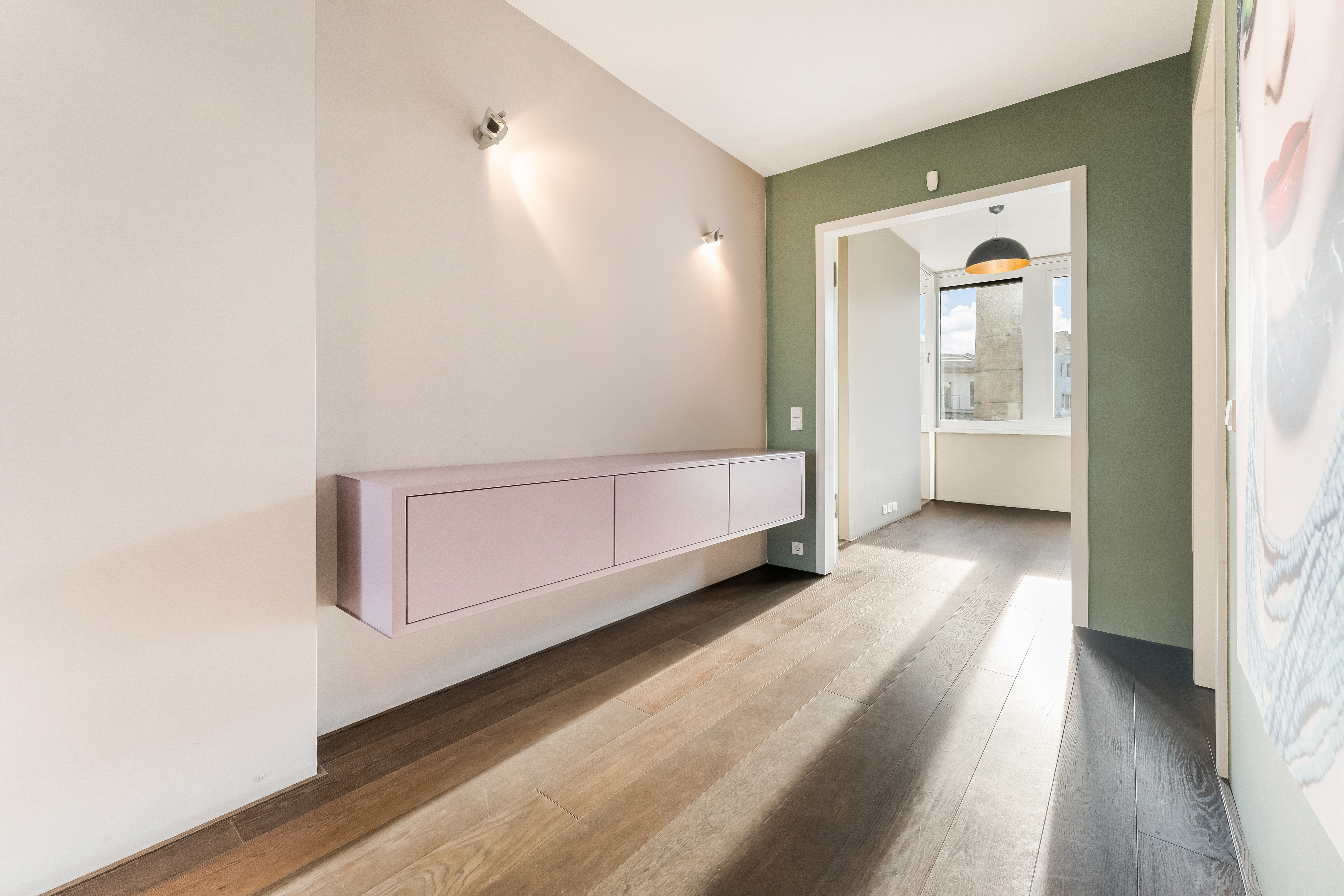 Heller Flur mit Holzfußboden, grün gestrichener Wand und hängendem Sideboard.
