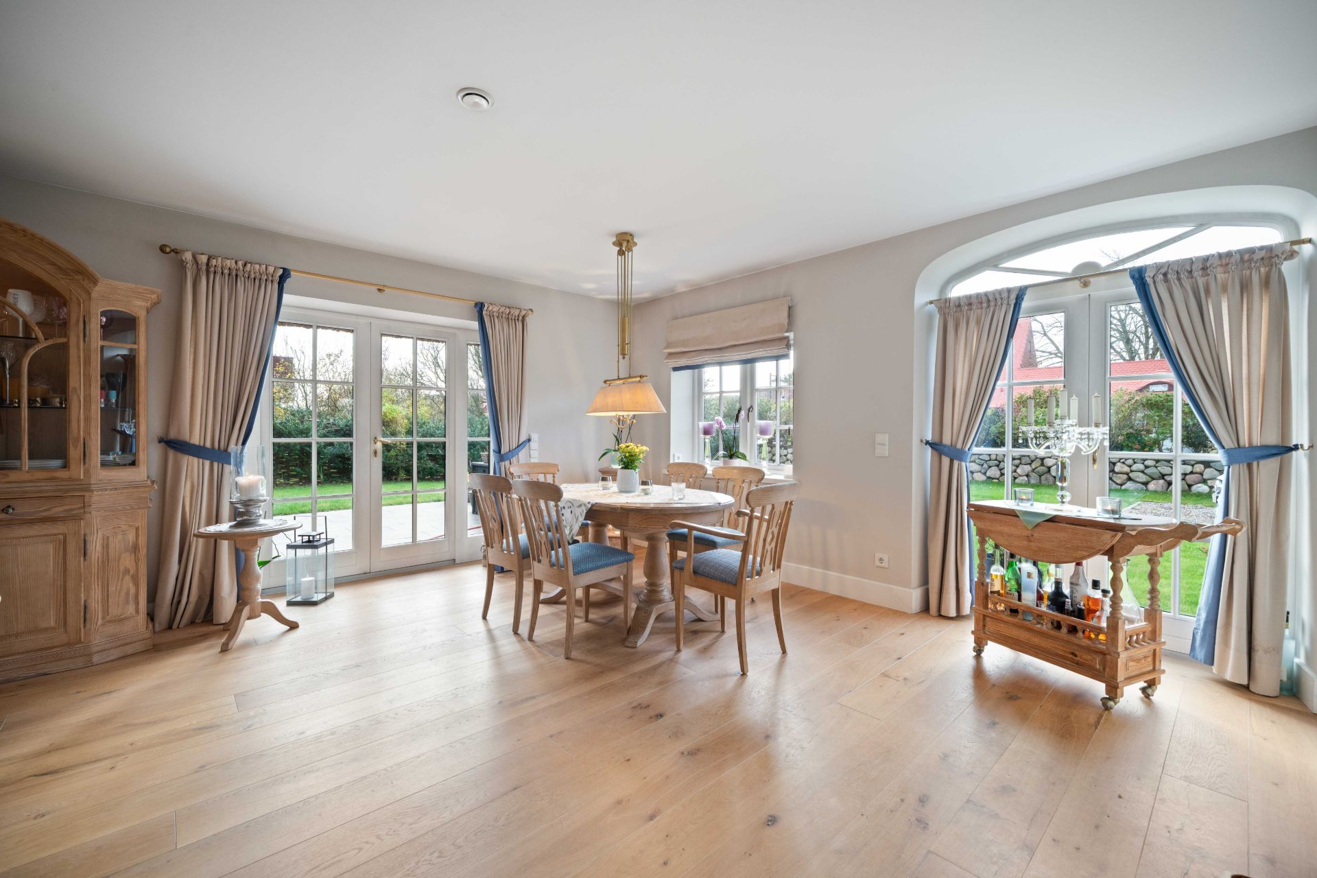 Helles Esszimmer mit Holztisch, Stühlen, Glasflügeltüren und Blick in den Garten.
