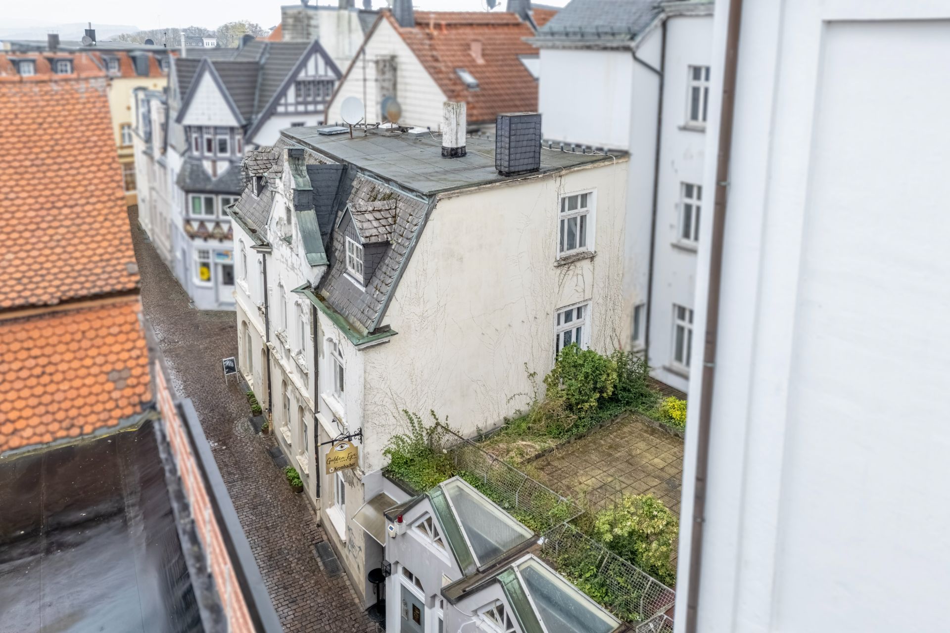 Blick auf ein helles Wohnhaus mit Flachdach, Innenhof und umliegenden Gebäuden.