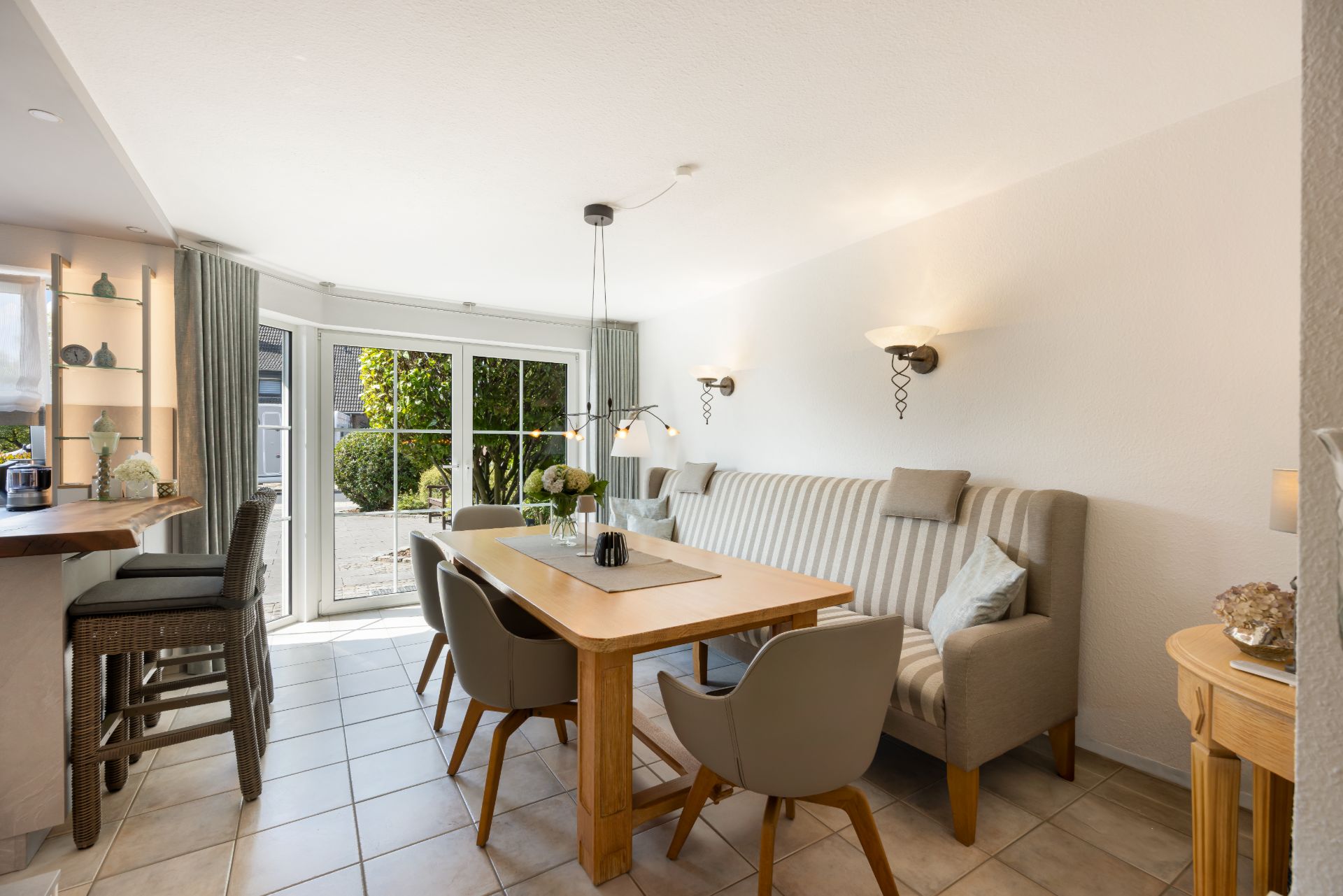 Helles Esszimmer mit Holztisch, Stühlen, Eckbank und Zugang zur Terrasse durch große Glastüren.