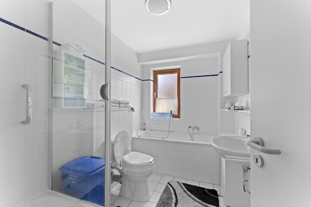 Helles Badezimmer mit Dusche, Toilette, Waschbecken, Badewanne und Fenster.
