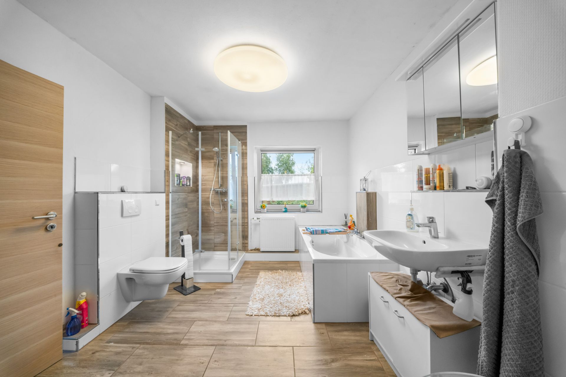 Modernes Badezimmer mit Dusche, Badewanne, WC, Waschbecken und großem Spiegel.