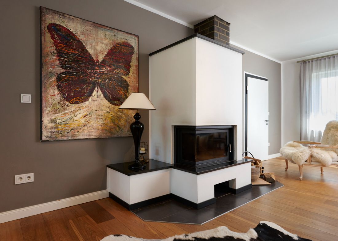 Modernes Wohnzimmer mit Kamin, großem Schmetterlingsbild, Stehlampe und Holzfußboden.
