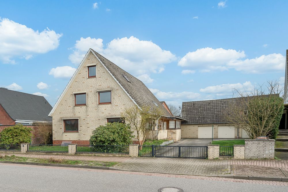 Zweistöckiges Einfamilienhaus mit spitzem Dach, Garage und Vorgarten an einer Straße.