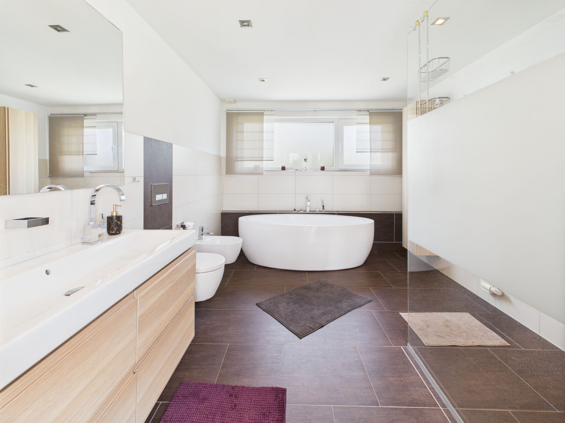 Modernes Bad mit Badewanne, Doppelwaschbecken, Dusche und zwei Fenstern.